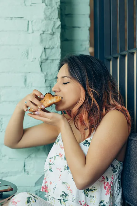 a woman is eating a panini