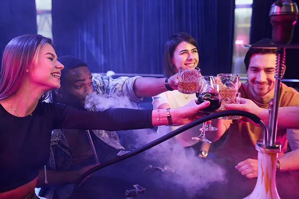 a group of friends smoke shisha and have some drinks